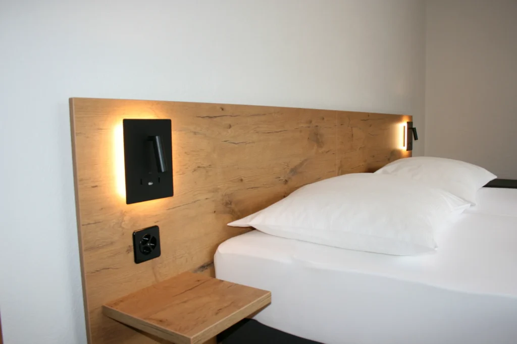 Detail von Bett, Holzkopfteil und integrierter Leselampe