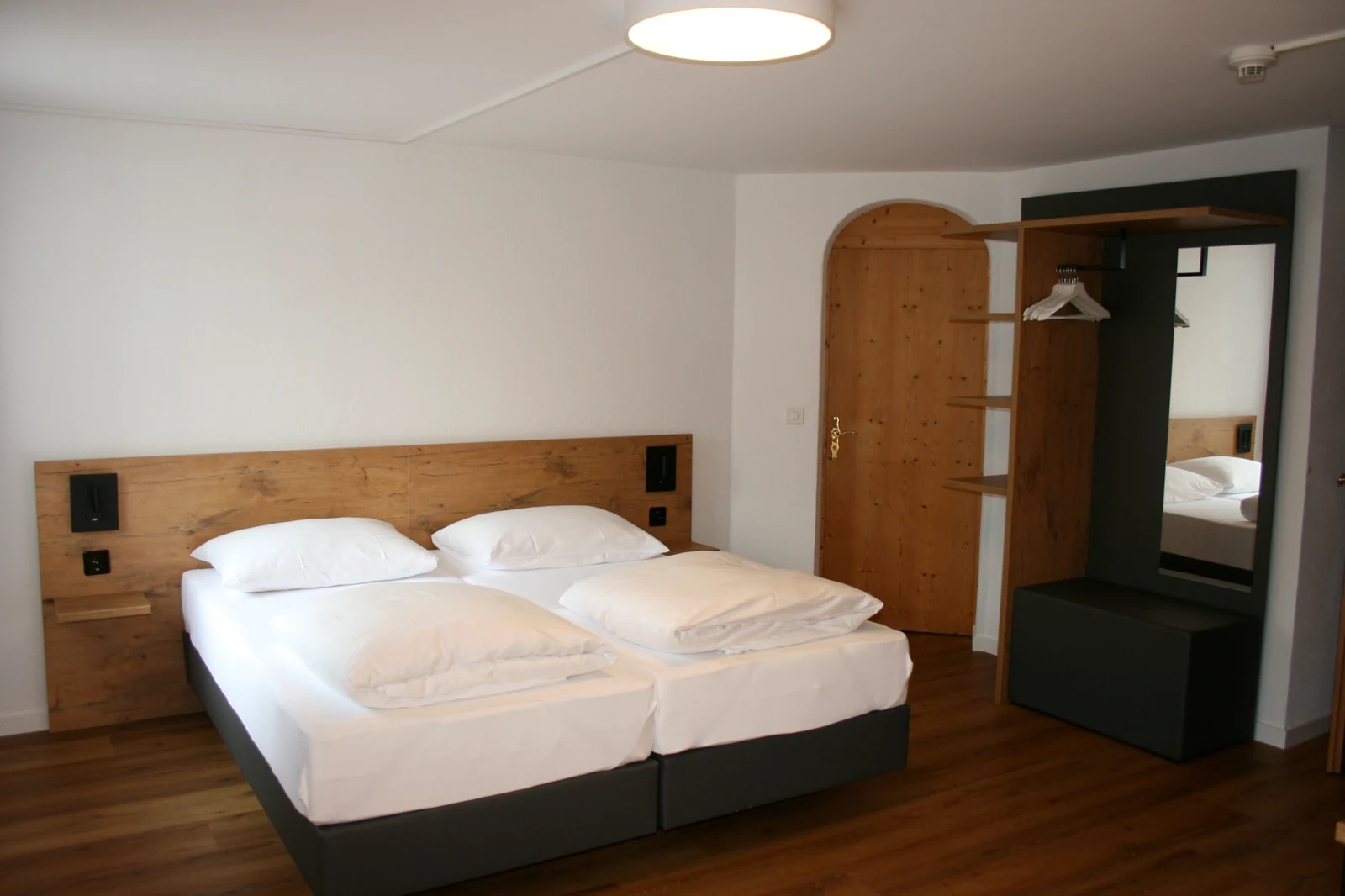 Zimmer mit Boxspringbetten, Holzkopfteil und offener Garderobe