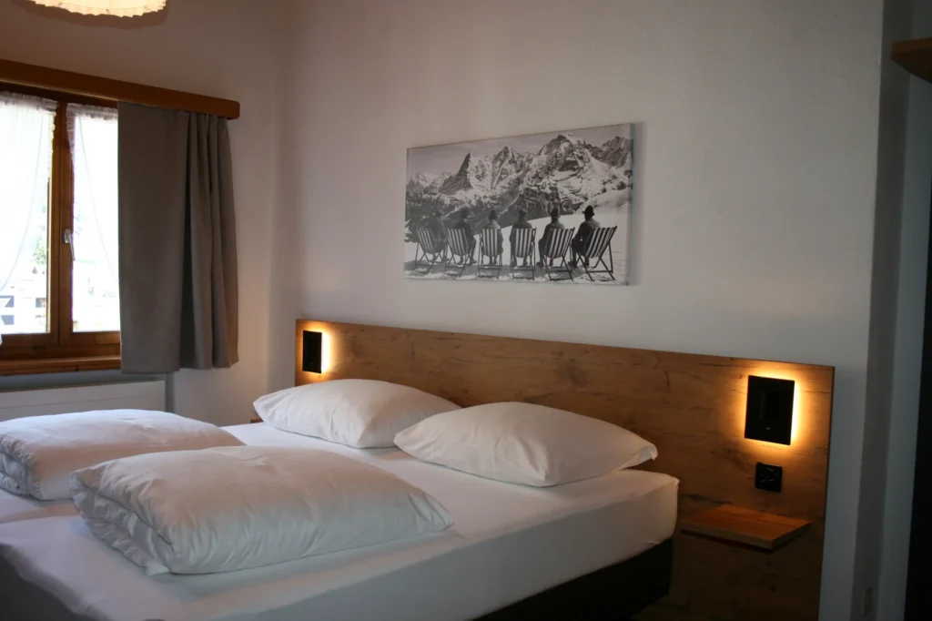 Doppelbett mit Holzkopfteil und Bergbild im Dachzimmer