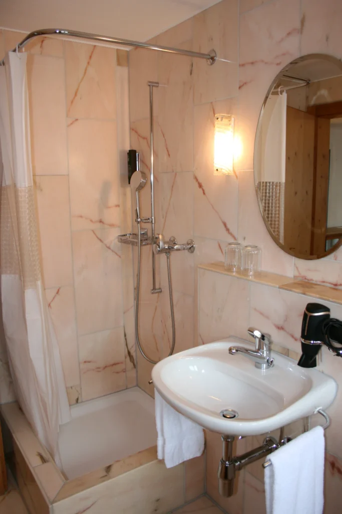 Badezimmer mit Dusche, Waschbecken und Spiegel